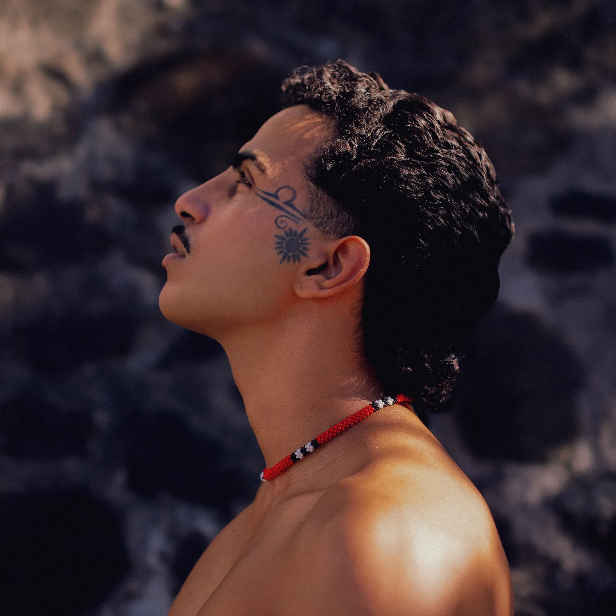 Fatel de perfil, com a tatuagem de sol visível